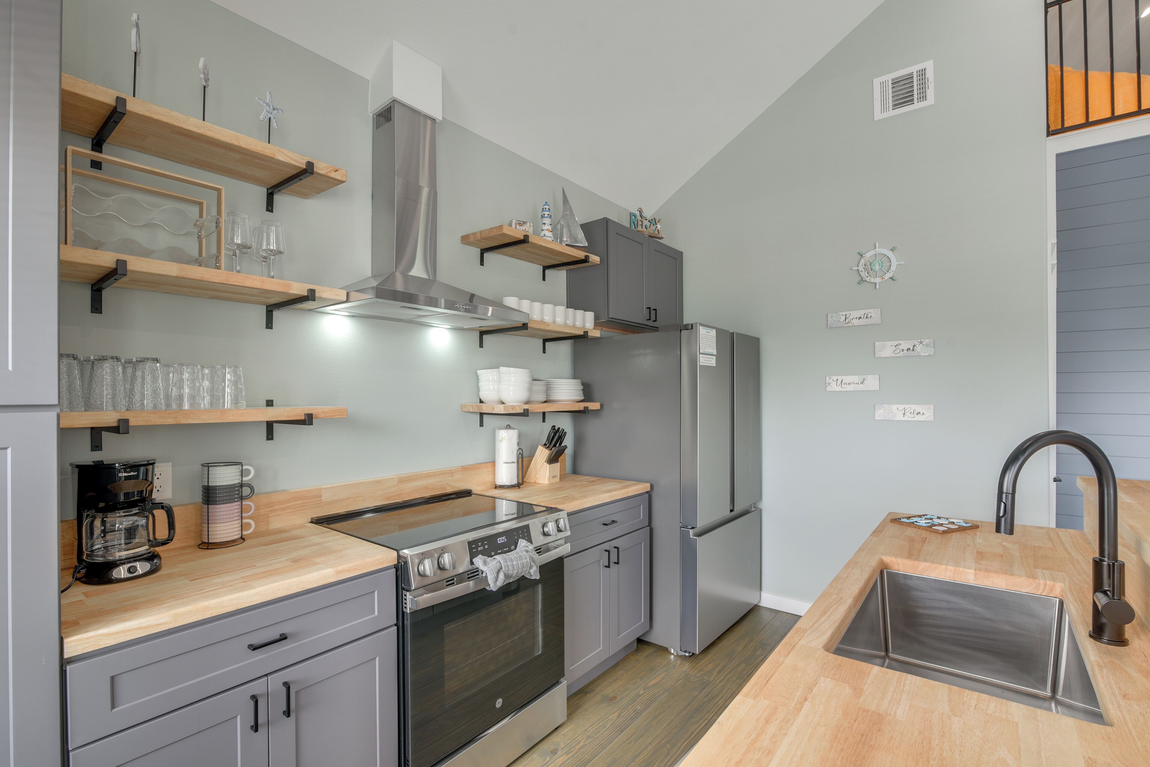 A modern kitchen with wooden shelves, a stainless steel range, and a built-in oven.