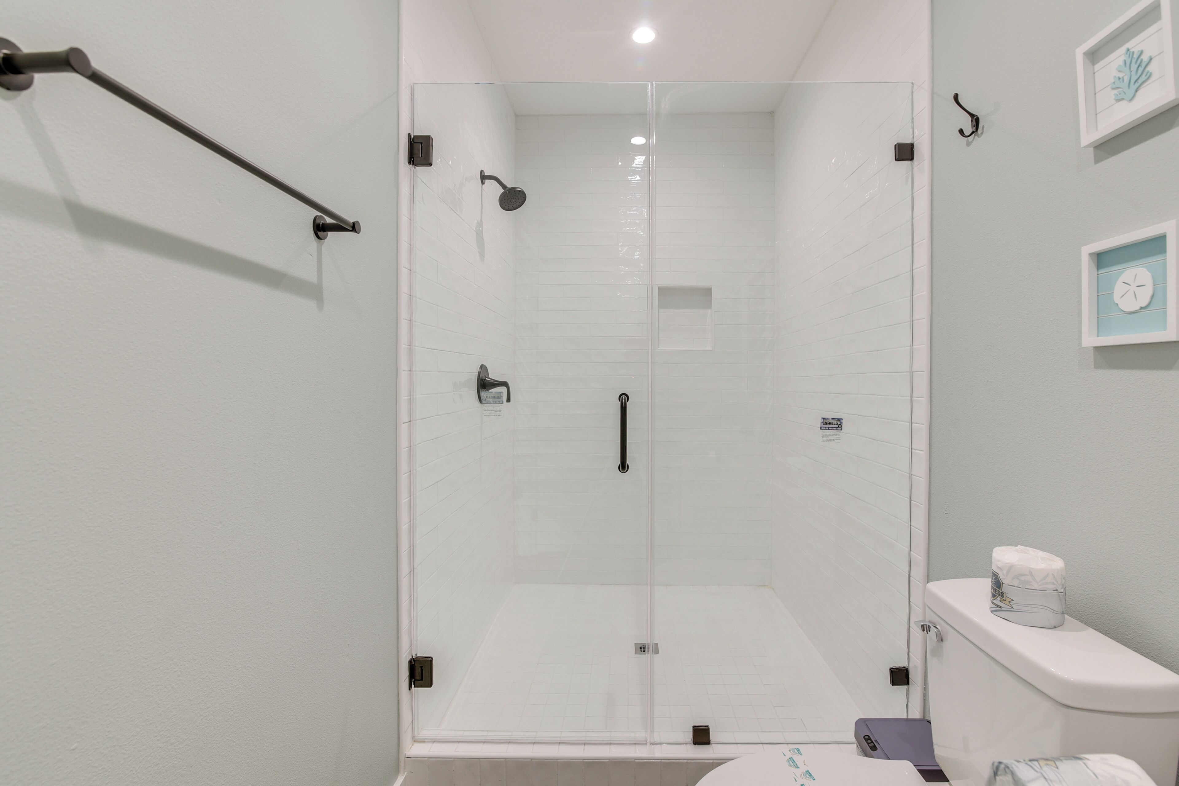 A modern bathroom with a glass-enclosed shower, a toilet, and a small sink.