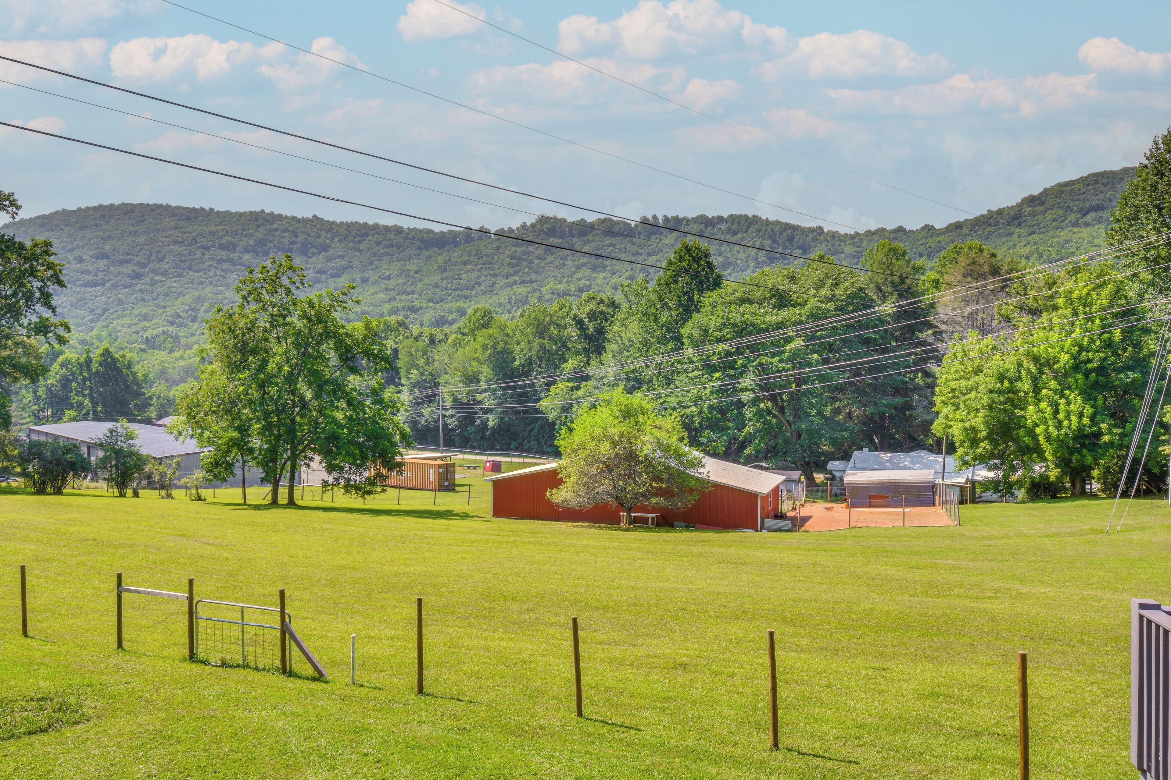 Propiedad rural con un campo cercado, un granero rojo y una casa con techo inclinado.