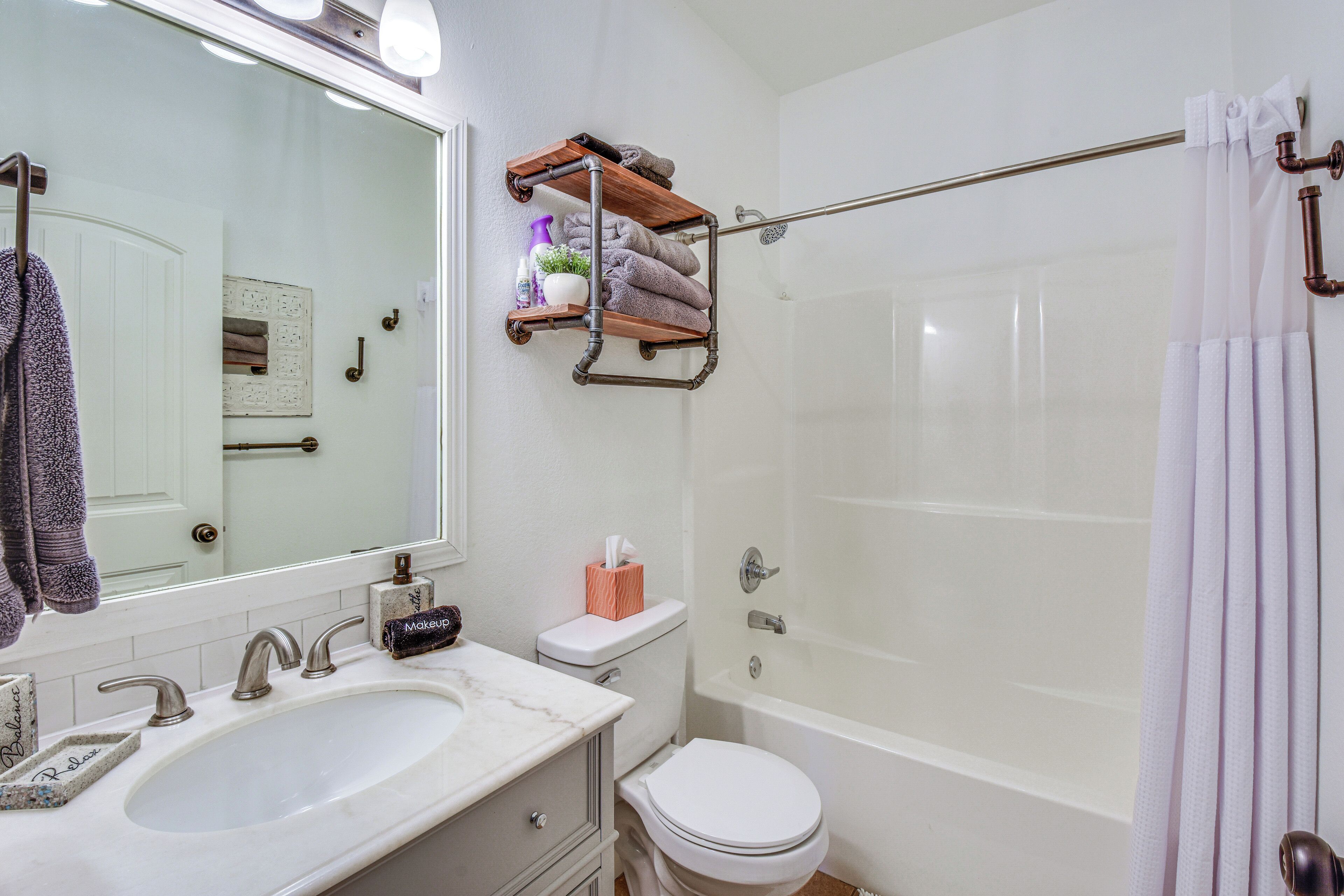 A bathroom with a white sink, a toilet, a bathtub, and a shower curtain.
