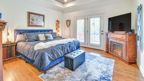 A bedroom with a large bed, a fireplace, a television, and a ceiling fan. - Hiawassee Cabin Near Lake Chatuge + AT Trailheads (Hiawassee)