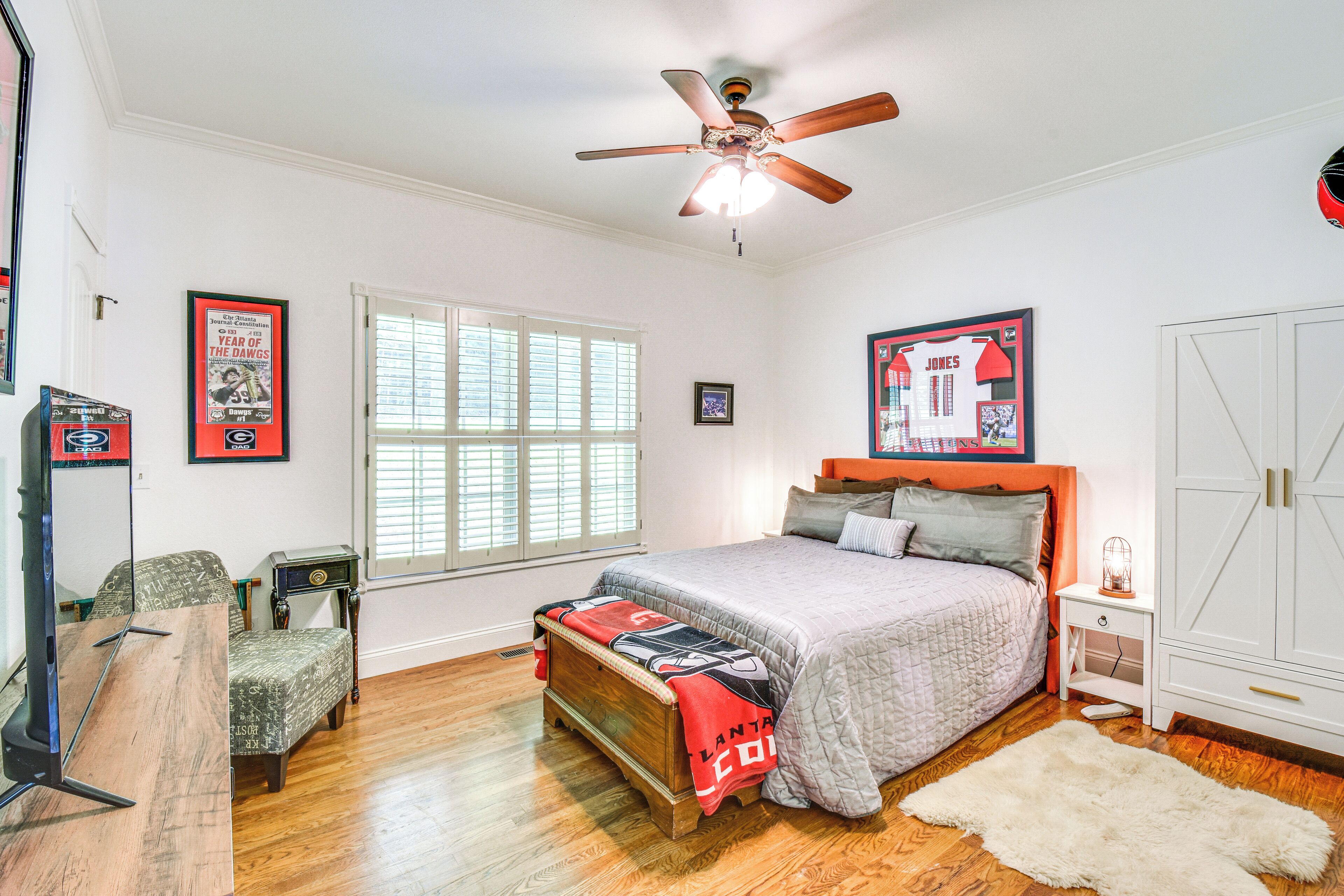 Une chambre à coucher comprenant un lit, un ventilateur de plafond, une fenêtre, une table de chevet et une armoire.