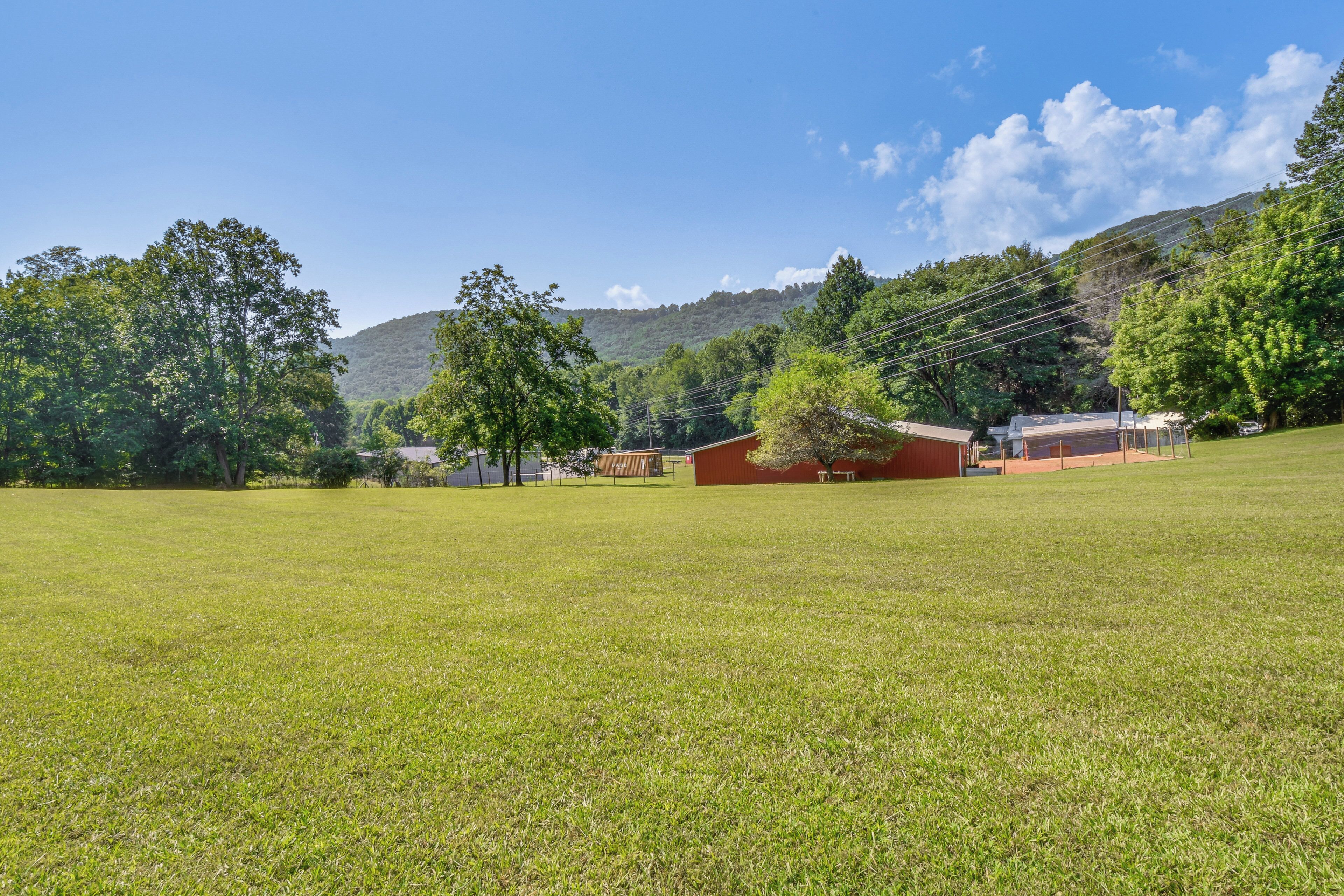 A grassy field with a building and trees in the background.