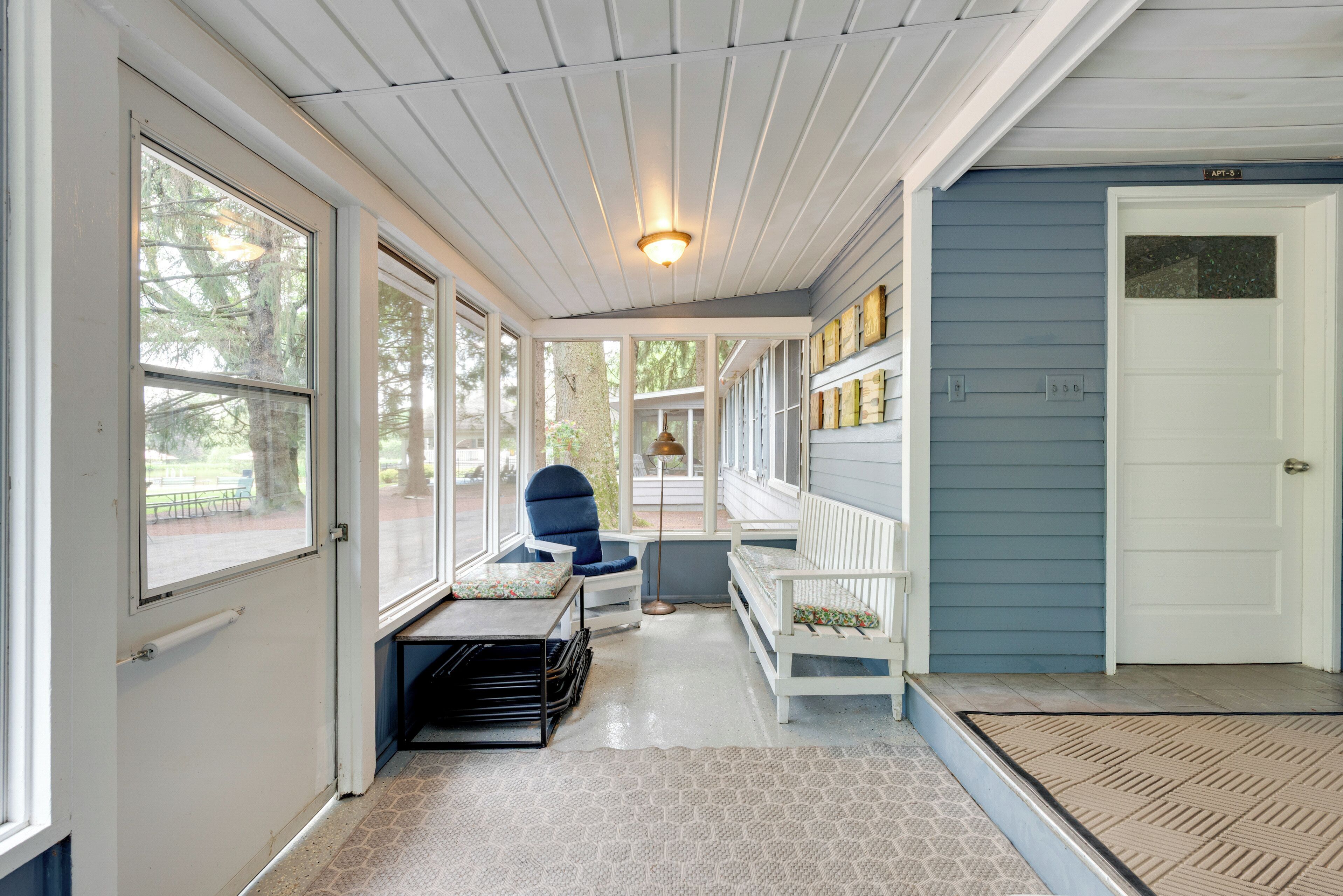 A covered porch with a bench, a chair, and a small table.