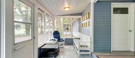 A covered porch with a bench, a chair, and a small table.
