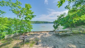 A lakeside picnic area with benches and picnic tables, surrounded by trees and a wooden fence. - Indoor Pool Access: Cabin in Lakes of the North! (Elmira)