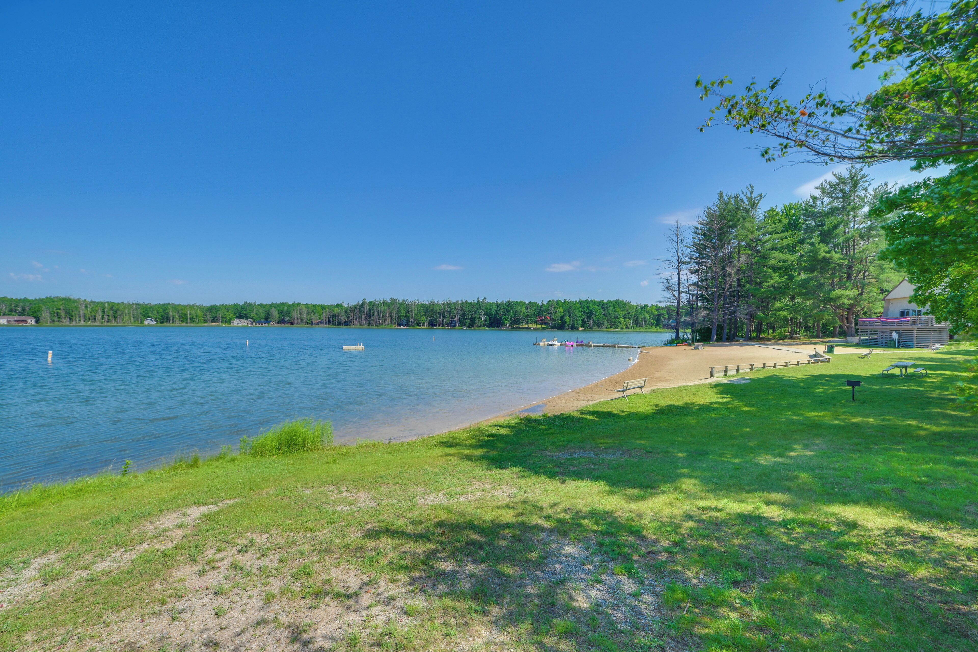 A lakeside view with a grassy area, a dock, and a small building.