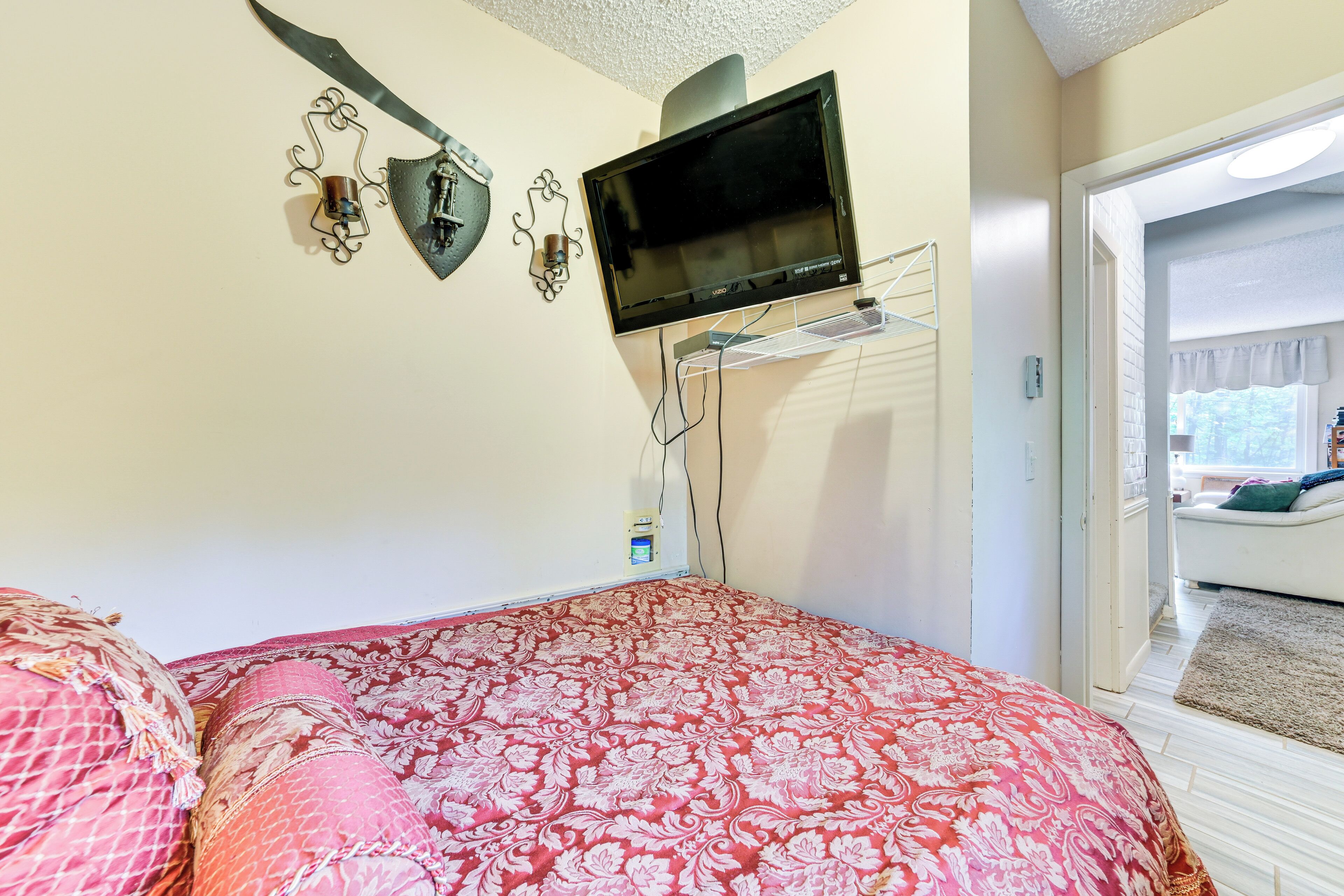 A bedroom with a bed, a television mounted on the wall, and a door leading to another room.