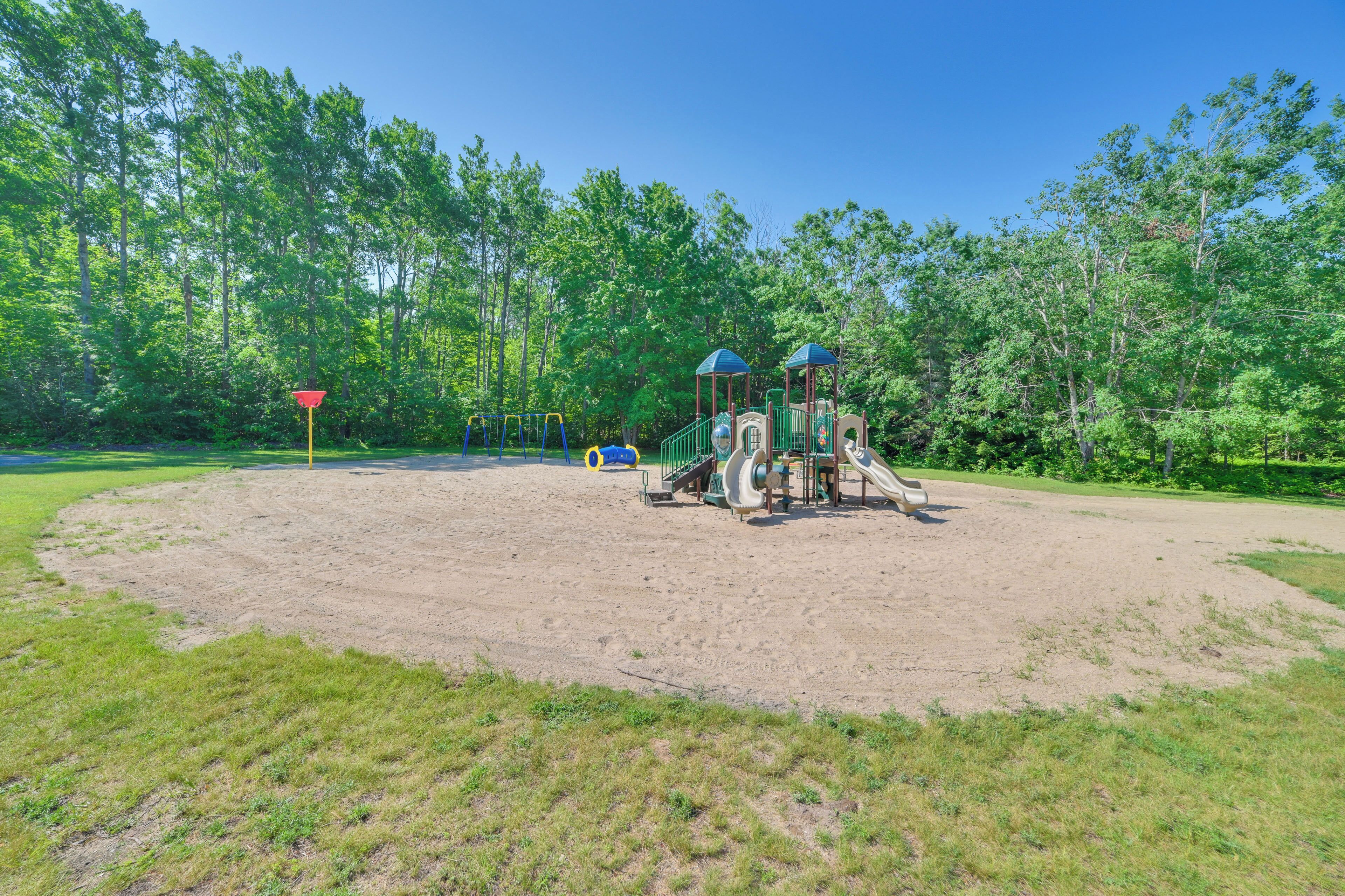 A playground with slides and climbing structures, surrounded by trees and grassy areas.