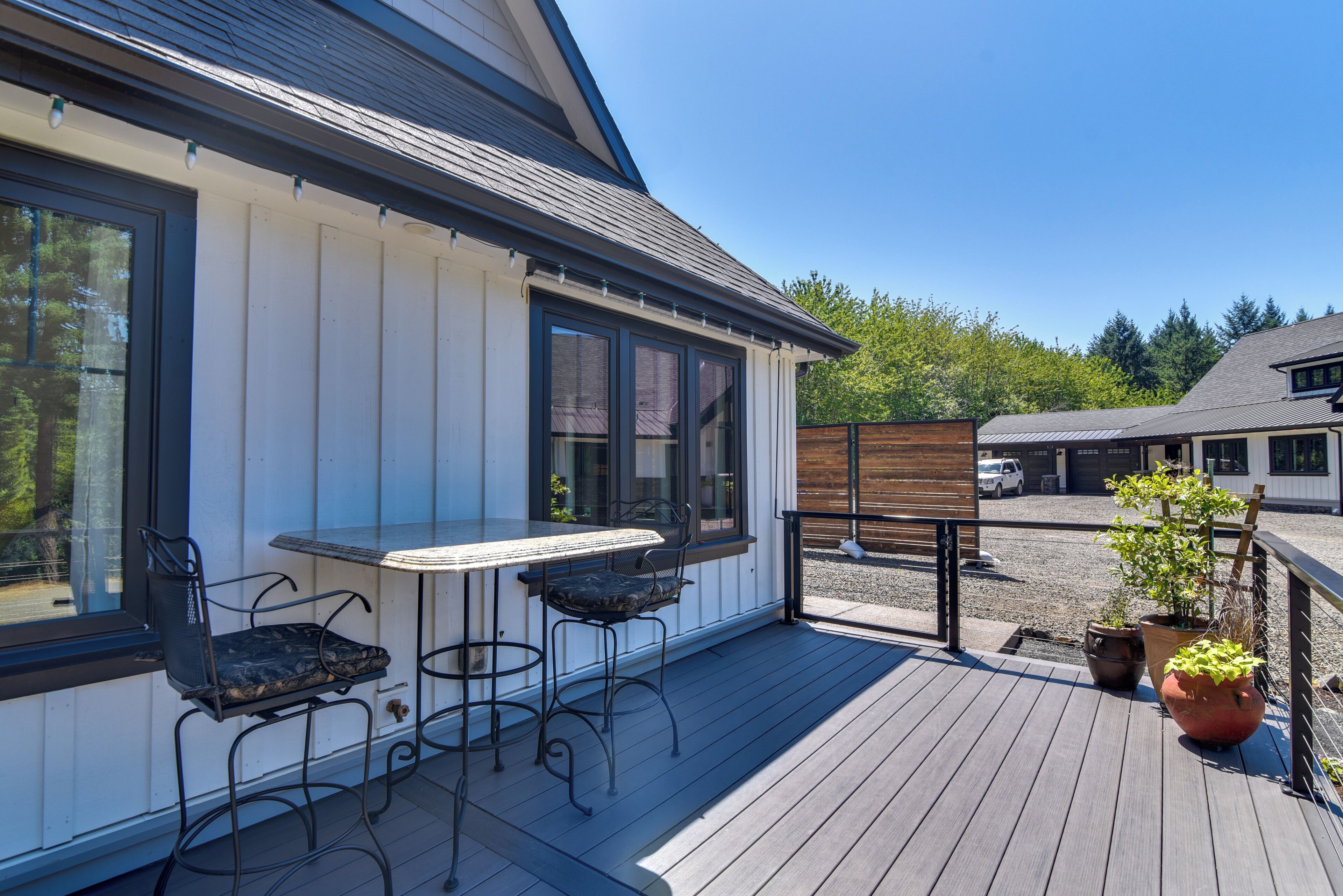 A covered outdoor area with a table and chairs, a wooden deck, and potted plants.