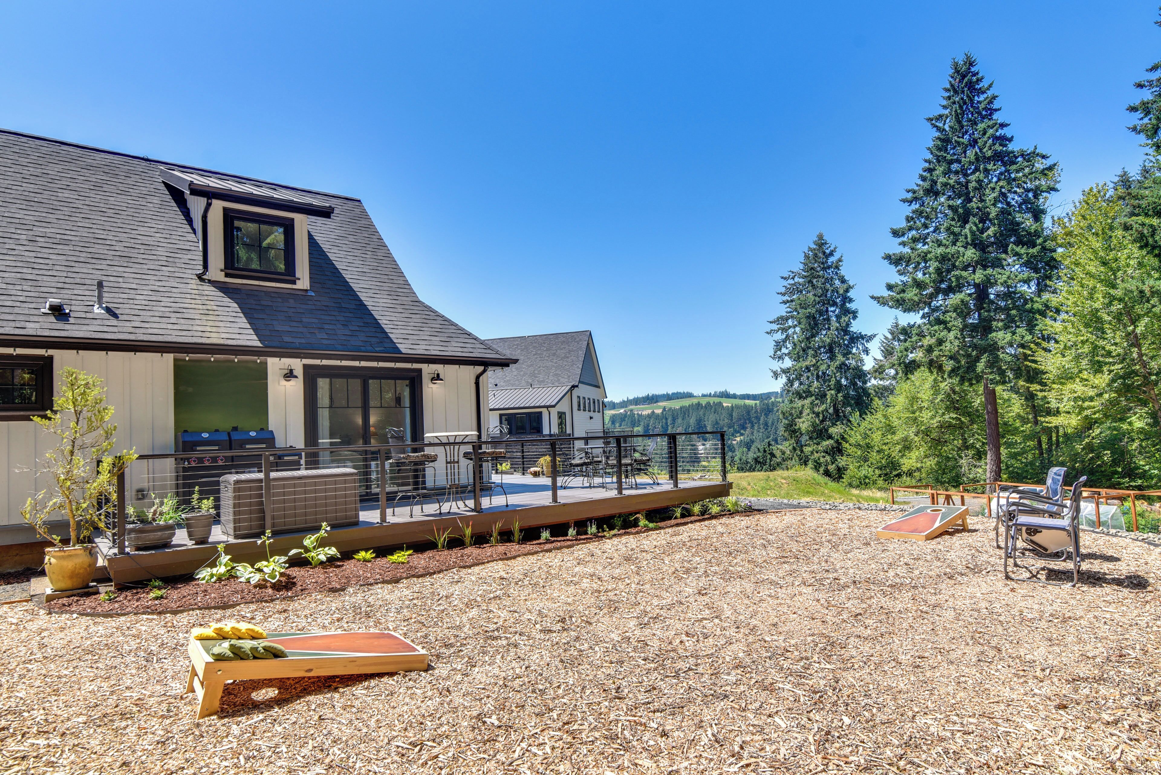 Une maison dotée d’une terrasse, d’un espace salon extérieur et offrant une vue sur les arbres et les collines.
