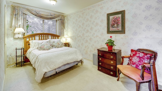 Quarto com cama, mesas de cabeceira, cômoda, cadeira e janela com cortinas.