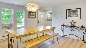 A dining area with a wooden table and bench, a decorative hanging light, and a framed picture on the wall. - Steps to Saco River: Outdoor Rec Hub in White Mtns (Conway)