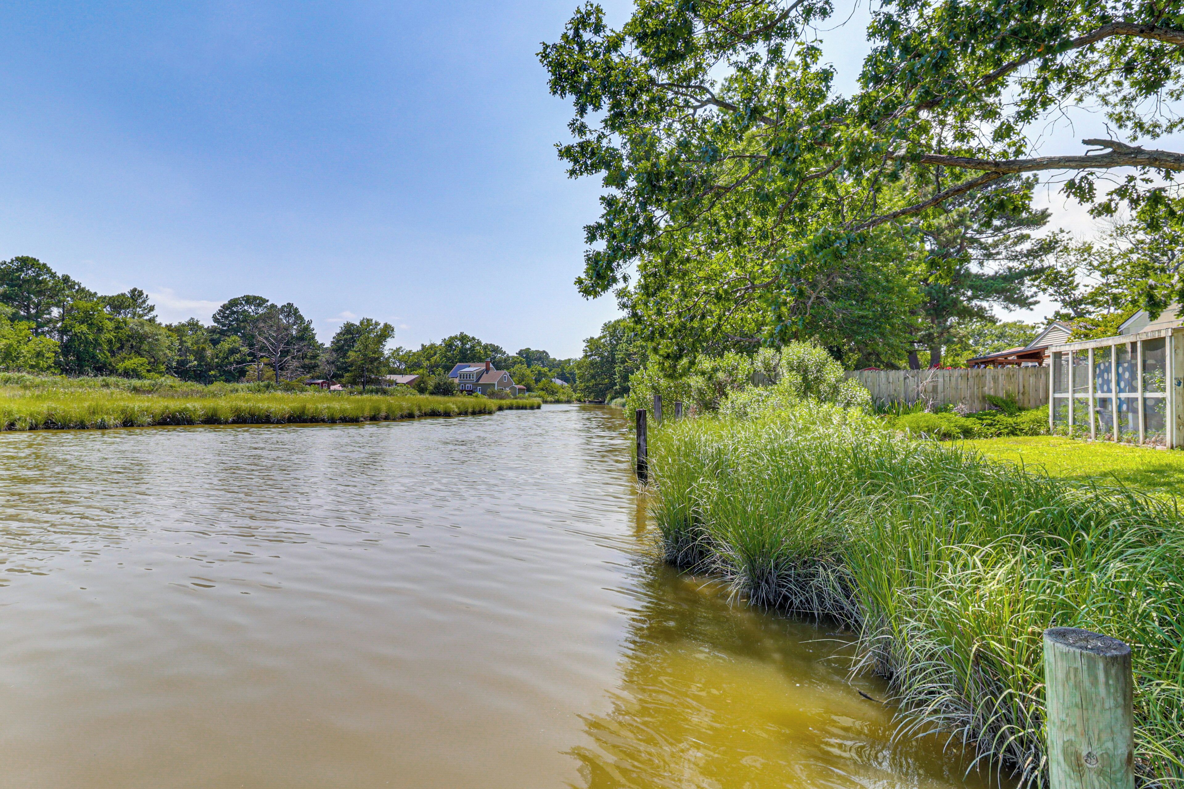 A river with a wooden fence and grassy banks.
