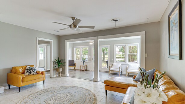 A spacious living room with a yellow sofa, a round rug, and a ceiling fan. - Riverfront Fun: Quiet Home Near Hampton Coastline (Hampton)