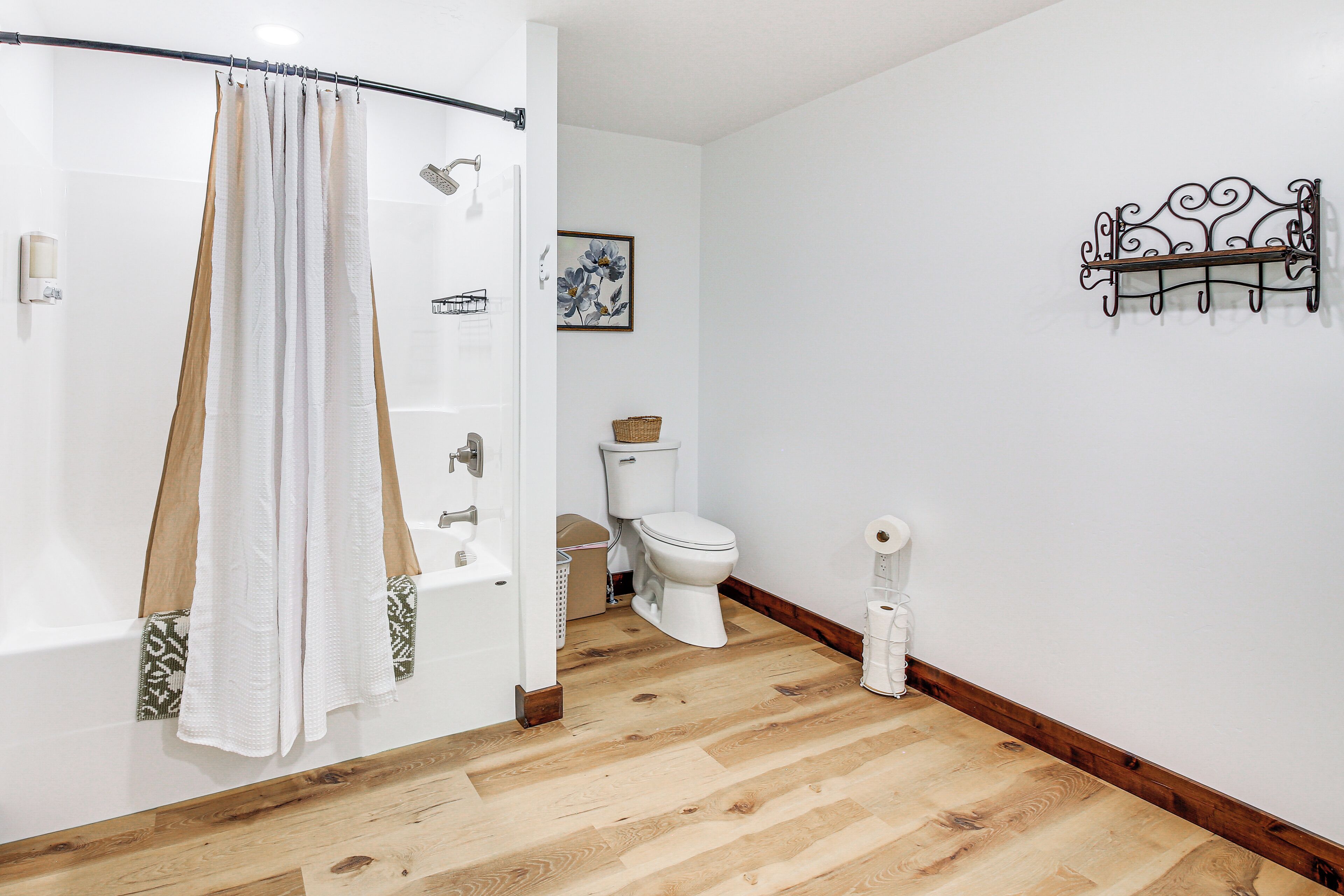 A bathroom with a shower curtain, a toilet, a sink, and a wall-mounted towel rack.