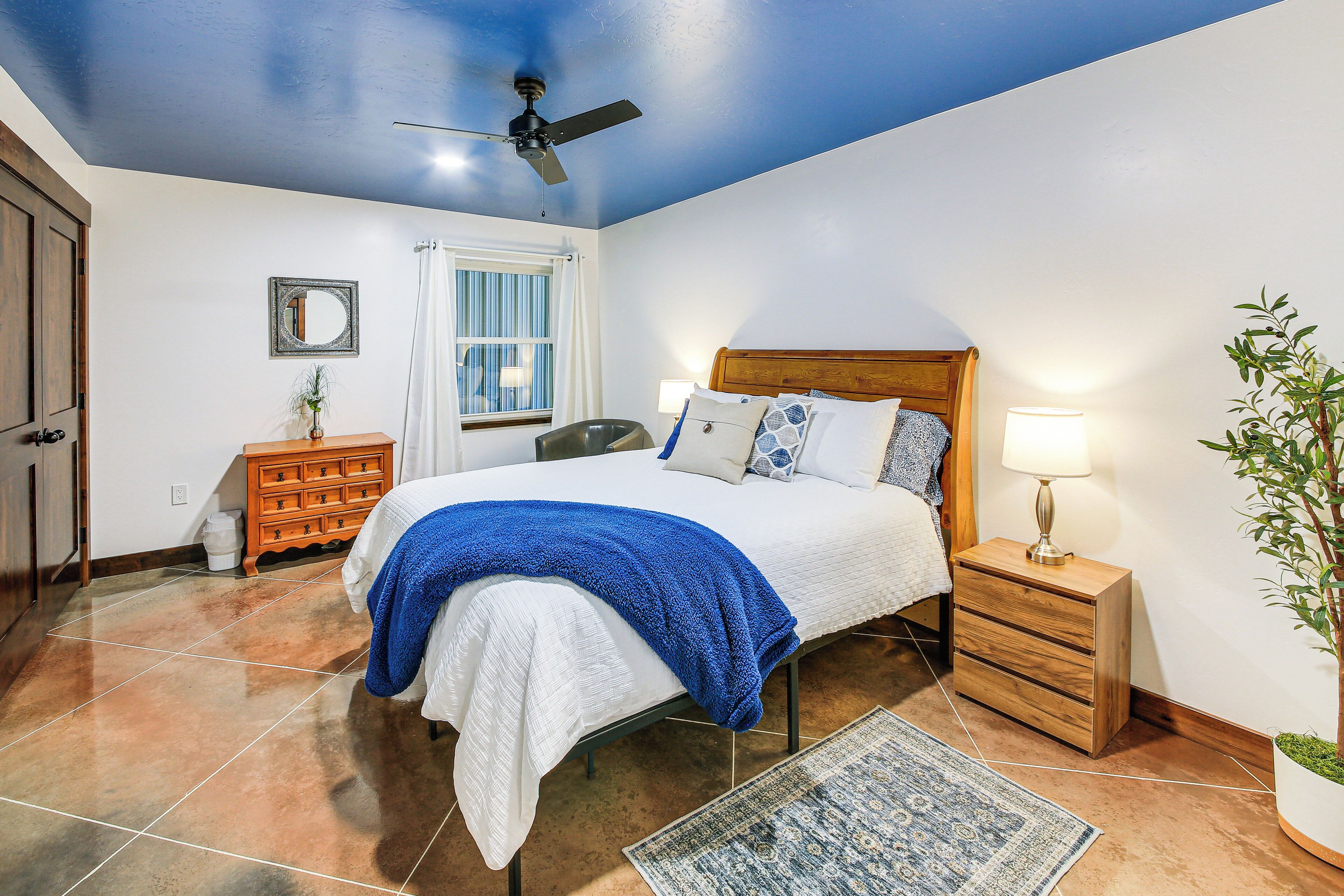 A bedroom with a bed, nightstand, dresser, and a ceiling fan.