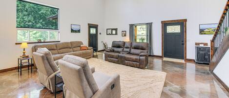 A spacious living room with a large window, a fireplace, and a staircase.