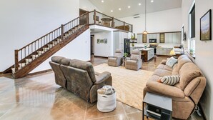 A spacious living area with a large sofa, a recliner, and a staircase leading to an upper level. - Relax, Reconnect & Explore: Modern Idaho House! (Naples)