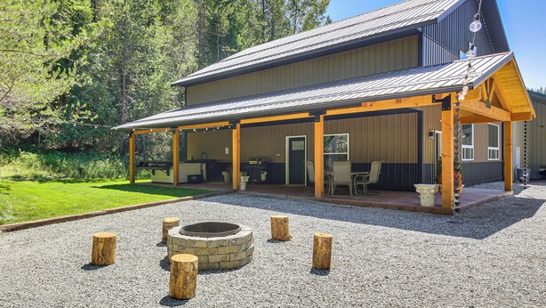 A large building with a covered patio area, a fire pit, and a gravel driveway. - Relax, Reconnect & Explore: Modern Idaho House! (Naples)