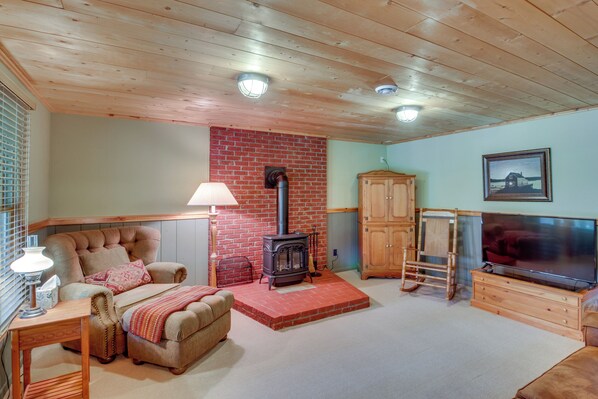 Una sala de estar acogedora con chimenea, sofá, televisor y armarios de madera.