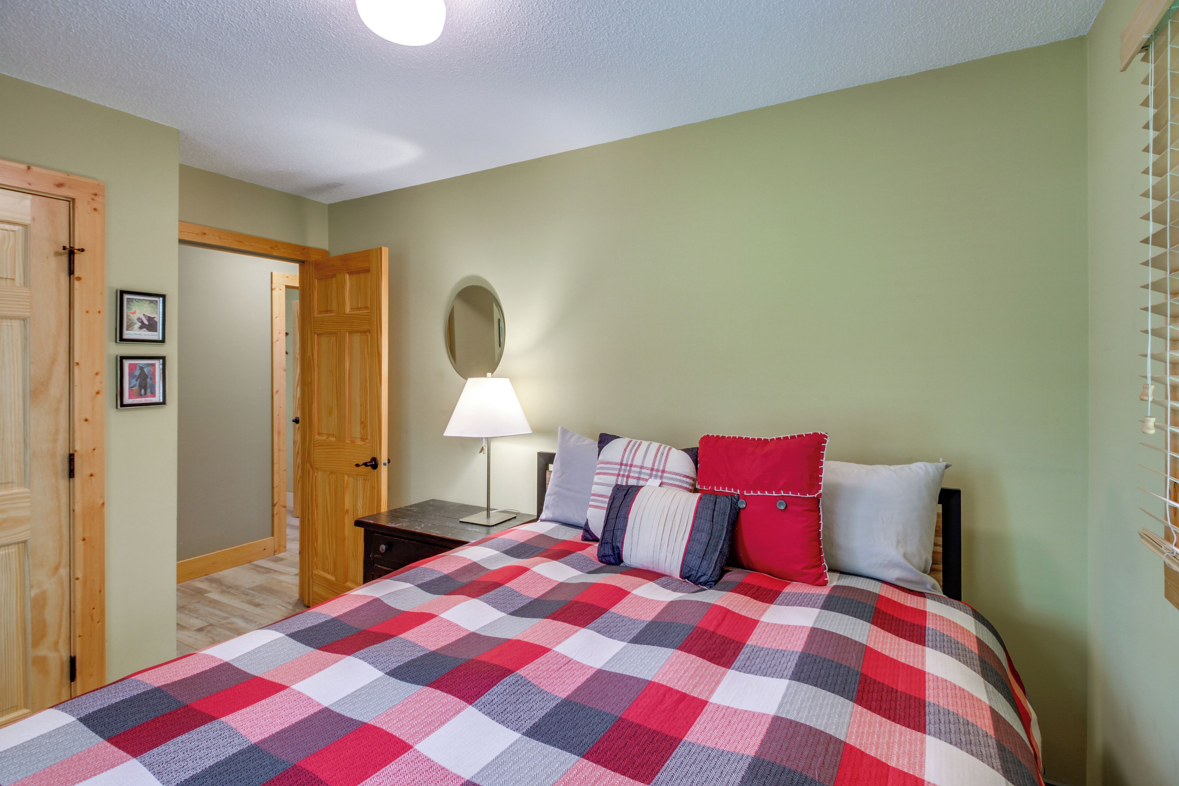 Une chambre à coucher avec une couvre-lit à carreaux, une lampe de chevet et un miroir au mur.
