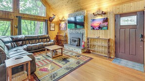 A cozy cabin interior with a stone fireplace, leather sofa, and large windows overlooking the forest. - Serene Mountain Home: 11 Mi to Gettysburg (Fairfield)