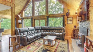 A large wooden interior with a leather sectional sofa, a stone fireplace, and large windows overlooking a forest. - Serene Mountain Home: 11 Mi to Gettysburg (Fairfield)