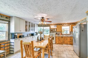 A spacious kitchen with wooden cabinets, a large island, and a ceiling fan. - Woodsy 20-acre Retreat w/ Hot Tub in Mancelona (Mancelona)