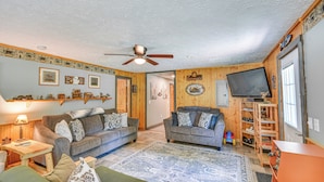 A cozy living room with two sofas, a coffee table, a TV, and a wooden ceiling fan. - Woodsy 20-acre Retreat w/ Hot Tub in Mancelona (Mancelona)
