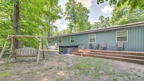 A rustic cabin with a wooden swing set, a covered outdoor seating area, and a small deck. - Woodsy 20-acre Retreat w/ Hot Tub in Mancelona (Mancelona)