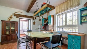 Une cuisine dotée d’un îlot central, de tabourets de bar, d’un meuble en bois et d’une fenêtre avec des rideaux.