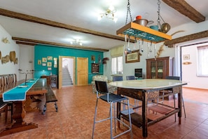 A dining area with a long wooden table, chairs, and a hanging pot rack.