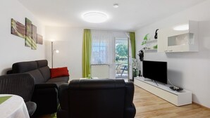 Een moderne woonkamer met een bank, een televisie en een eethoek.