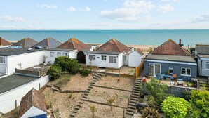 Una zona residencial costera con casas, cielo despejado y el mar al fondo.