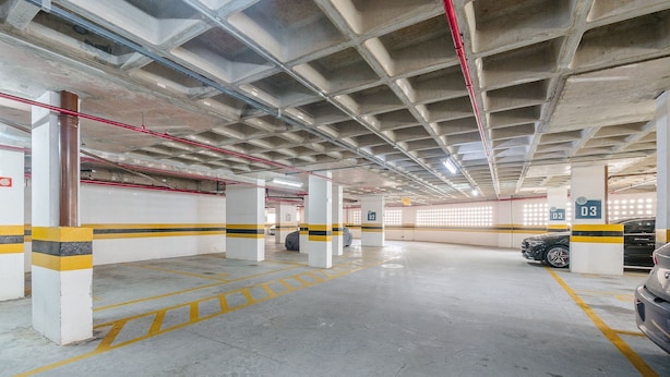 An indoor parking garage with concrete pillars, yellow and black striped barriers, and a clean, well-lit floor. - Beautiful Apartment 500m From Shopping Csp1207 (Salvador)