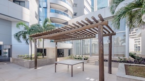 An outdoor seating area with a pergola, a table, and planters with various plants. - Beautiful Apartment 500m From Shopping Csp1207 (Salvador)