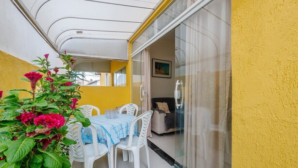 Un balcon avec une table et des chaises, des murs jaunes et une porte vitrée donnant sur un espace de vie.