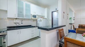 Une cuisine moderne avec des meubles blancs, un plan de travail noir et un coin repas comprenant une table et des chaises.