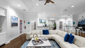 A spacious living room with a white sectional sofa, a coffee table, and a ceiling fan.