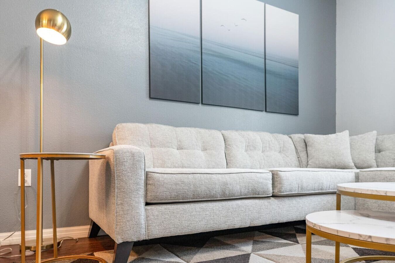 A modern living room with a grey sofa, a round coffee table, and a floor lamp.