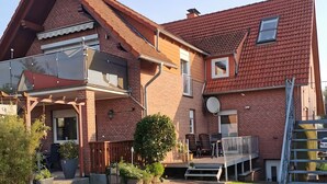 A two-story house with a balcony, a satellite dish, and a well-maintained garden.