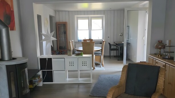 A spacious living area with a fireplace, a dining table, a wicker chair, and a round coffee table.
