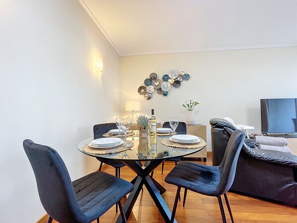 Un'area pranzo con un tavolo in vetro, sedie nere e una parete decorativa.