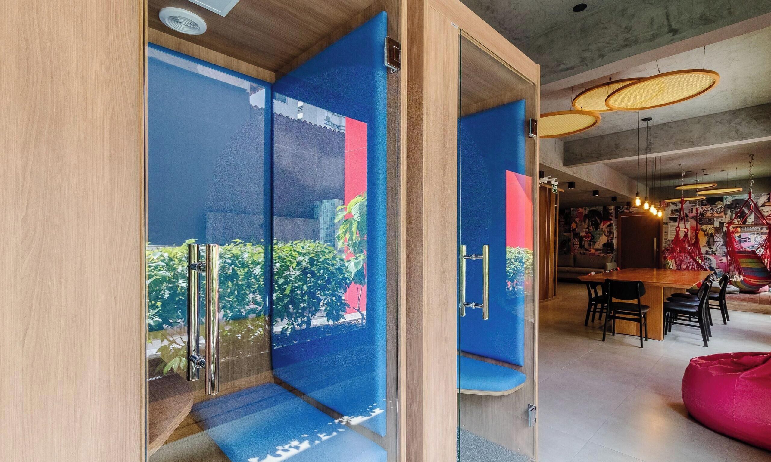 A modern interior with a glass partition, a wooden door, and a dining area with a table and chairs.