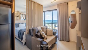 Een moderne hotelkamer met een bed, een sofa, een groot raam met uitzicht en een plafondlamp.