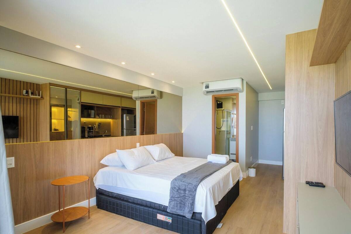 Ein modernes Schlafzimmer mit Bett, Nachttisch und Fernseher.