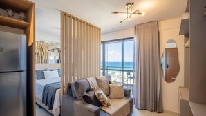Une chambre d’hôtel moderne équipée d’un lit, d’un canapé, d’une grande fenêtre offrant une vue et d’un luminaire au plafond.