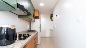 A modern kitchen with a gas stove, a built-in oven, and a refrigerator. - Beautiful Apartment in Salvador Rmo0602 (Salvador)