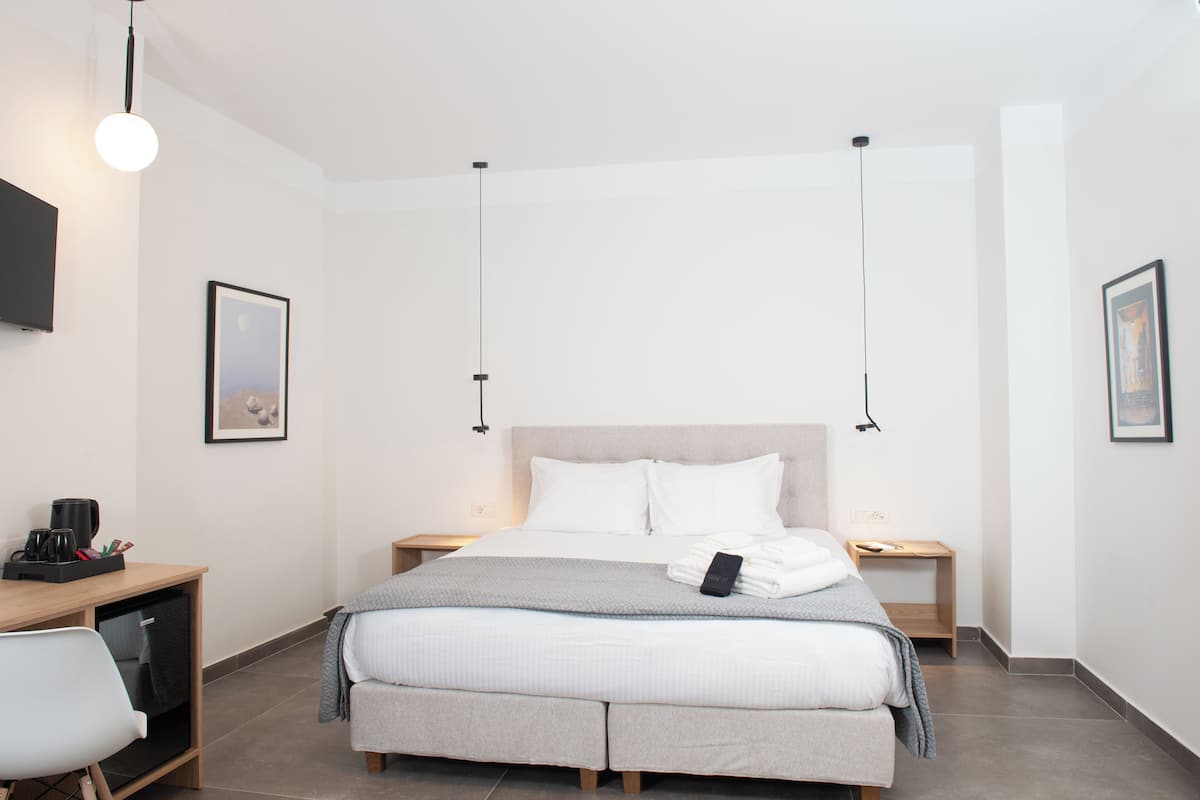 A modern hotel room with a large bed, bedside tables, a desk, and a chair.